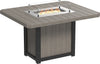Square outdoor dining table made of weather-resistant material with a built-in fire pit and glass wind guard.