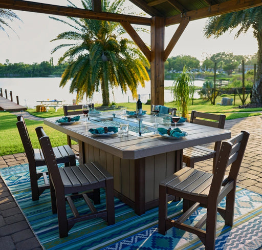 A family enjoying a meal around a LuxCraft rectangular fire pit table on a beautiful summer evening.