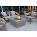 light grey round fire pit table in outdoor patio area. fire pit is lit on lava rocks