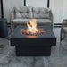 round fire table lit on lava rocks next to lounge furniture