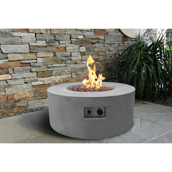 light grey fire table is lit on lava rocks next to plants in outdoor patio