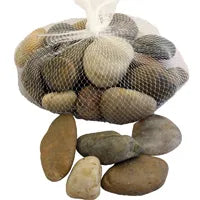 A white mesh bag filled with smooth, polished river stones in various shades of grey, tan, and brown. Several loose pebbles of similar colors are scattered below the bag on a white background.