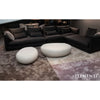 Two cream white Elementi Hawaii Steinform coffee tables are positioned in front of a dark sectional sofa on a patterned rug in a modern living room.