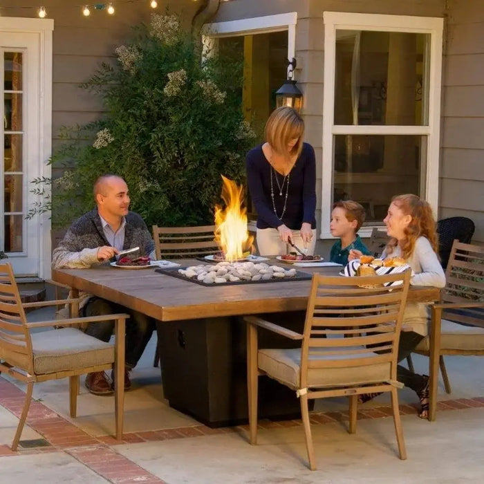 A cozy outdoor dining scene with a fire pit table taking center stage. The warm flames create a welcoming ambiance as chairs are arranged around the table, ready for a gathering.