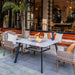 white marble outdoor dining table with glass wind screen and fire pit is lit in outdoor restaurant seating area 