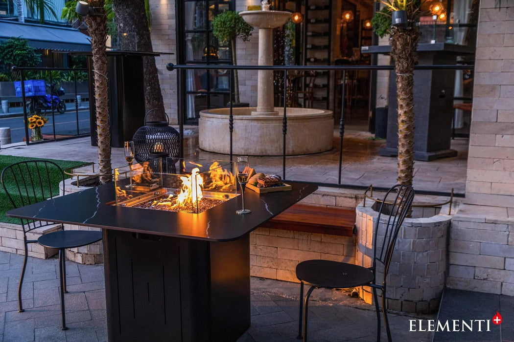 ootdoor dining table with a fire pit in the middle, fire pit is lit and table is set