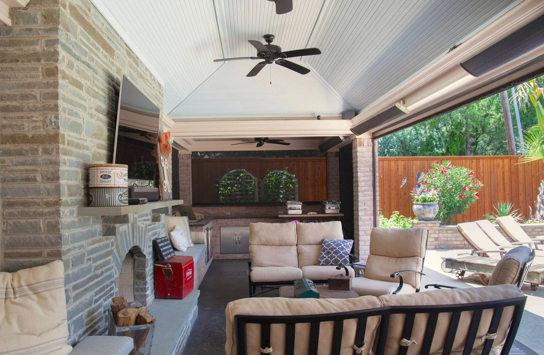 A well-appointed outdoor living area featuring a stone fireplace, plush seating, a ceiling fan, and a flat-screen TV.