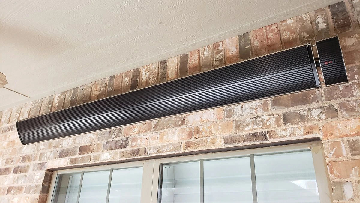 A sleek, black infrared heater installed on a brick wall, providing warmth for an outdoor space.