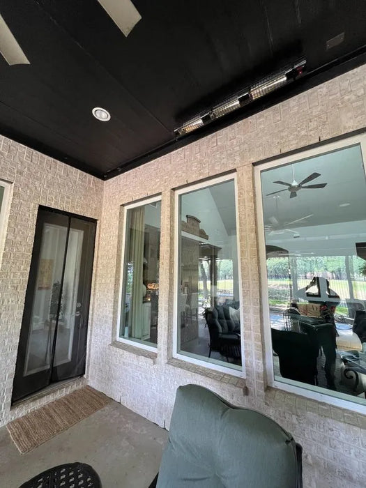 Indoor patio area with large windows, ceiling outdoor heaters, and outdoor furniture.