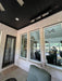 Indoor patio area with large windows, ceiling outdoor heaters, and outdoor furniture.