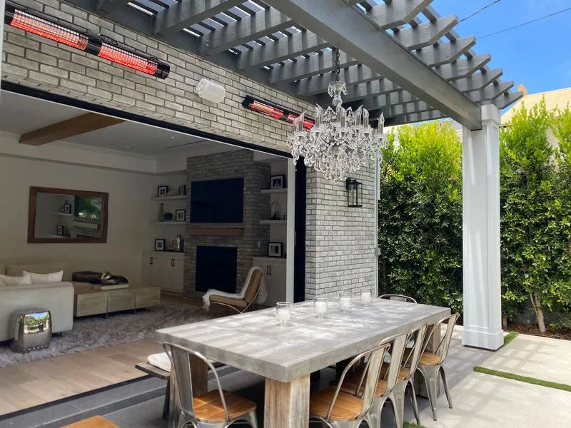 Outdoor patio with dining table, chairs, and chandelier under a pergola and patio heater