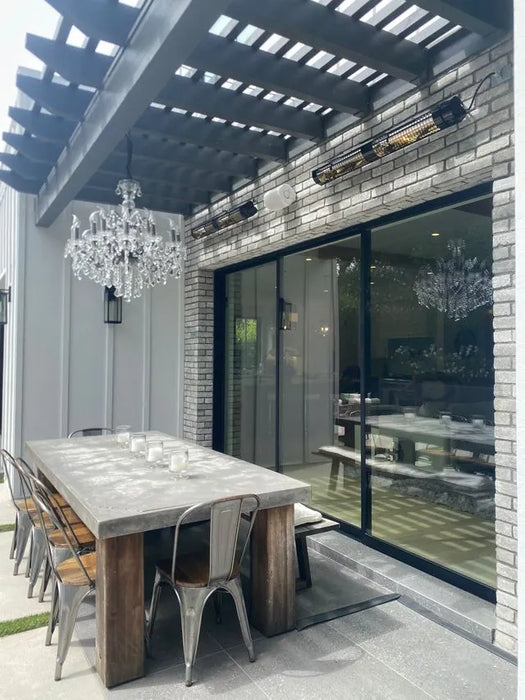 Modern outdoor dining area with a large table and chairs near a glass door.