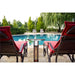 A RADtec Electric Bistro Patio Table Heater placed between two red lounge chairs on a patio overlooking a swimming pool.