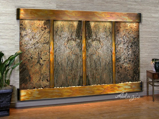 Regal Falls water wall fountain by Adagio, featuring a large rectangular natural stone surface with four vertical bronze-colored panels and a matching top and bottom frame, illuminated from within.