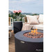 round fire pit table lit on brown lava rocks on outdoor rooftop next to outdoor sitting furniture