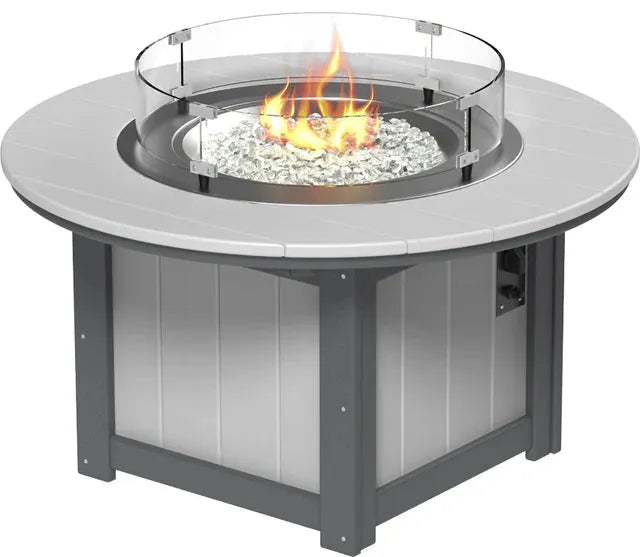 A LuxCraft Lumin 46" Dove Grey Round Fire Pit with a glass wind guard and a fire burning, showcasing white fire glass within.