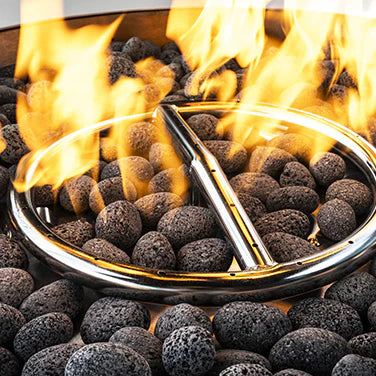 Detailed view of a vibrant yellow flame in a fire pit, with dark rocks and a silver metal ring surrounding the burner.