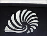 A close-up of a seashell cutout in a fire pit. The seashell is white against a dark background