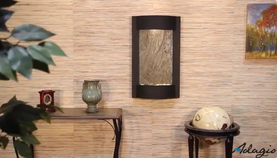 Decorative wall fountain with a globe and small table against a textured wall.
