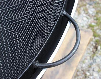  A close-up of a black metal handle on a spark guard. The handle is curved and has a mesh screen in the background.