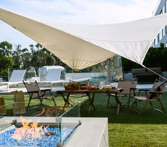 fire pit lit next to big umbreller with glass windscreen around fire pit