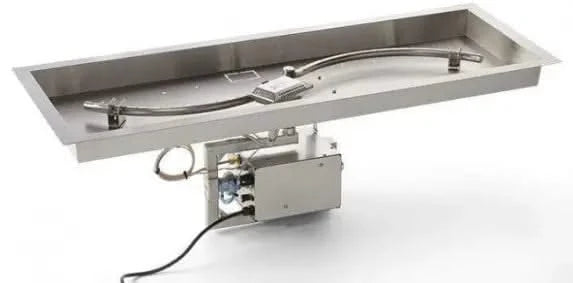 A close-up photo of a rectangular stainless steel gas fire pit burner with an S-shaped design. The burner has small holes drilled along its length, and flames are visible through the holes.