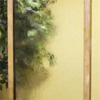 A close-up shot shows water flowing down the textured glass panel of the Adagio Harmony River water feature in a clear glass surface 
