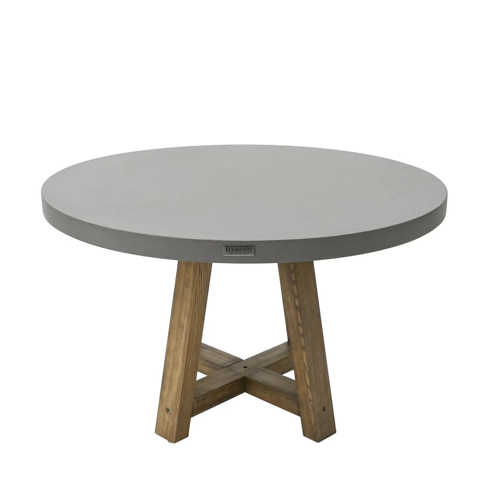 A 48-inch round outdoor dining table by Elementi Home, featuring a smooth, space grey concrete tabletop and a rustic wooden pedestal base with an X-shaped support.