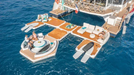 Floating platform with lounge chairs and people on a body of water