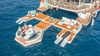 Floating yacht platform with lounge chairs and people on a body of water