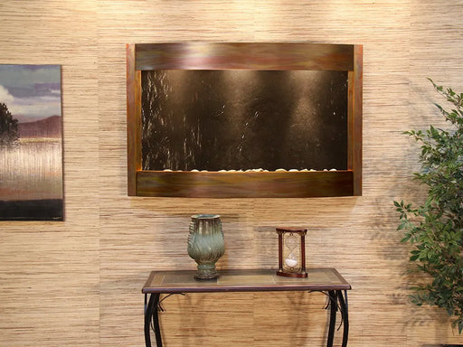 Wall-mounted water feature with a copper frame and dark slate panel.