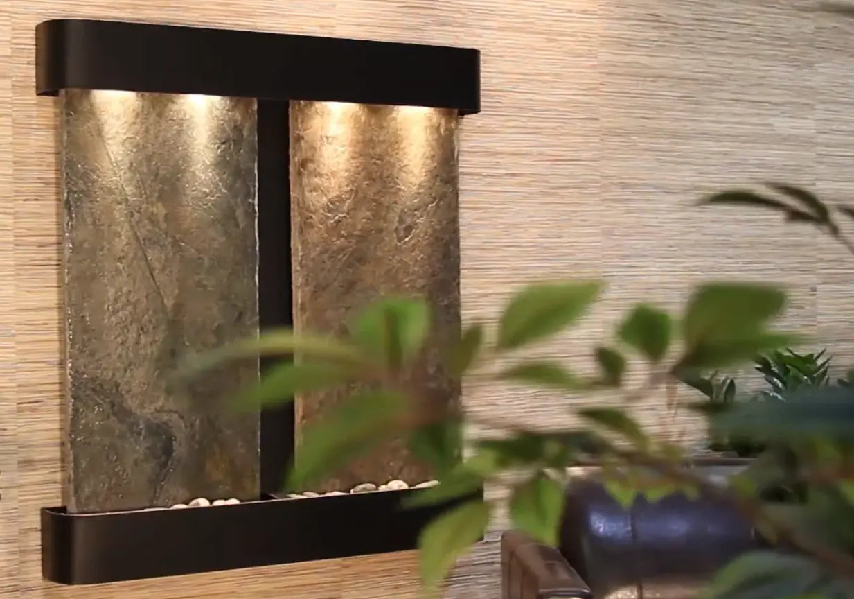 Decorative wall mounted water feature fountain with stone-like panels and black frame against a textured wall.