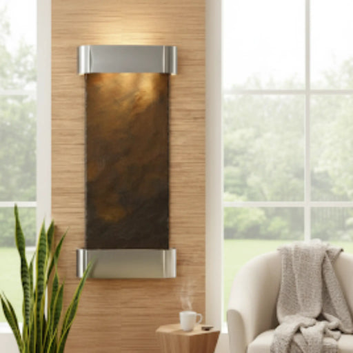 Decorative wall piece with a brown and silver design in a room with a couch and plant.
