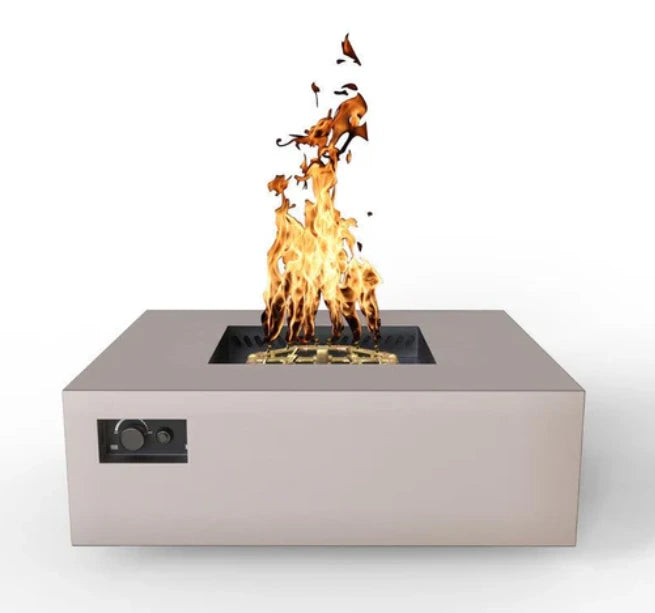 A front view of a square gas fire pit table with a sand pebble finish. Flames are dancing above the gold-colored burner. Controls are located on the side.