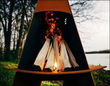  A close-up of a tall, conical wood-burning fire pit with flames burning inside. The fire pit is orange in color and has a deer logo on the side.