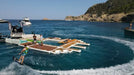 People on a floating water park yacht platform with boats and a scenic background