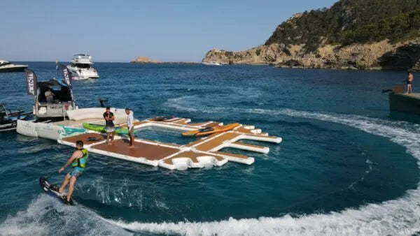 People on a floating water park yacht platform with boats and a scenic background