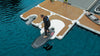 Person with a surfboard near an inflatable dock on water