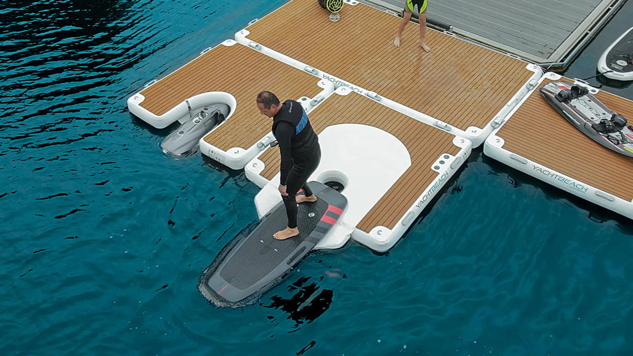 Person with a surfboard near an inflatable dock on water