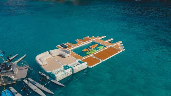 Floating platform with pool and boats on a clear blue water background
