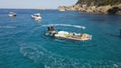 Boat on a raft in the middle of a clear blue sea with rocky cliffs in the background