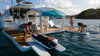 People on a catamaran with a canopy, preparing for water activities.