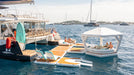 Floating lounge area on a body of water with people enjoying the sun.
