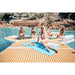 People relaxing on a wooden deck by a pool with inflatable dock