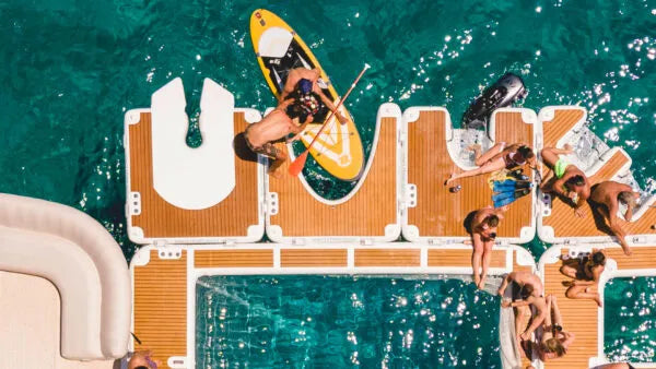 People enjoying a day at a pool party with a paddleboarder in the water.