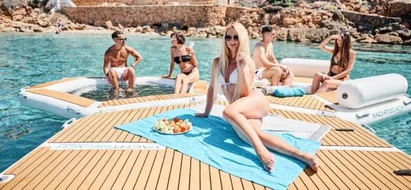 People relaxing on a sunlit dock by a pool with a scenic background