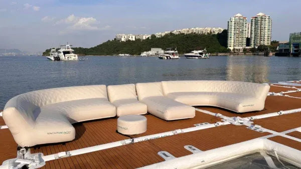 Inflatable sectional sofa on a dock by a body of water with buildings in the background
