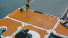 Two people on a large floating dock with water in the background