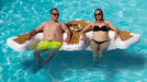 Two people relaxing on a floating island in a pool.