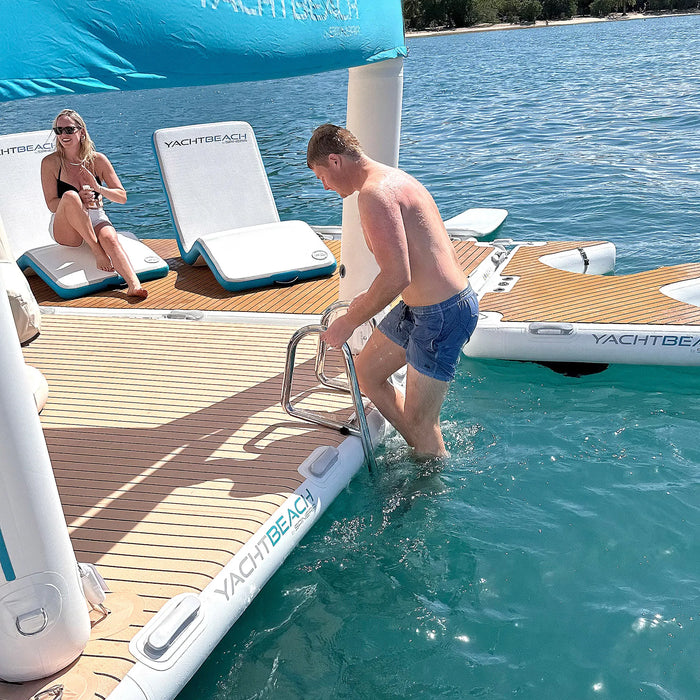 People on a Yacht Beach inflatable platform with a stainless steel dock ladder attached by a body of water